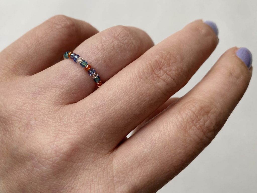 Seed Bead Ring in Artisans Cooperative Colors Shown on Finger of a Woman's Hand