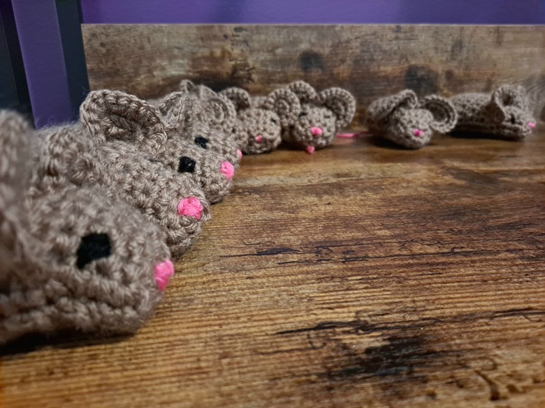 Line-up of handmade cute brown crocheted mouse amigurumi catnip cat toys on a wood floor