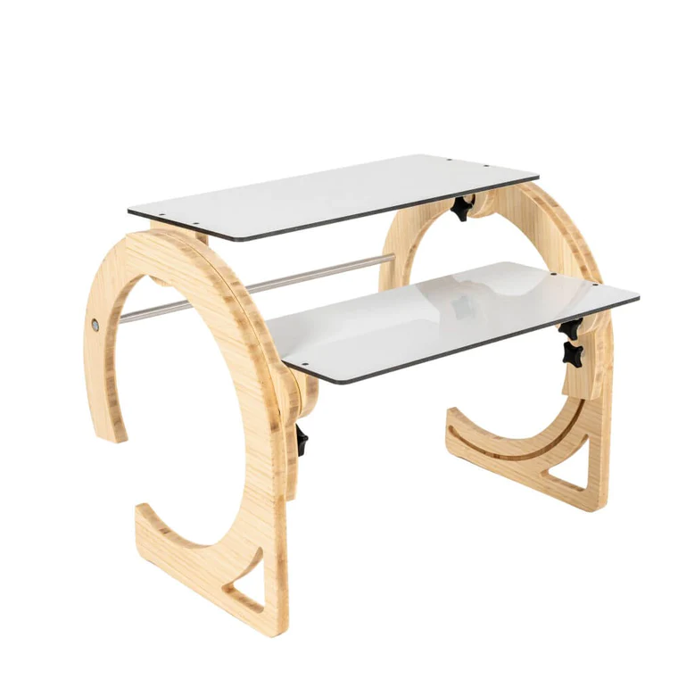 A photo of a portable laptop desk with two trays arranged in a stepped or ferris wheel style. The desk's light wooden legs are curved in a shape similar to a crescent moon, with the ends a few inches from completing a full circle. 