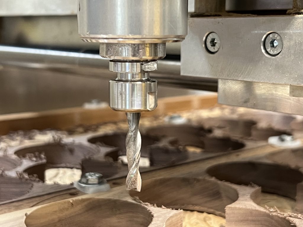 A CNC machine cutting perfect circles out of walnut wood for mason jar lids. Credit Schuttenworks.