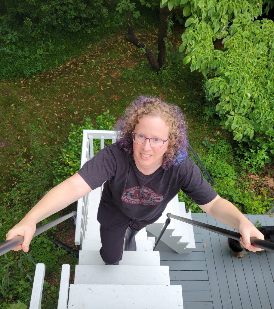 An outdoor photo of Erin from above as she climbs up a set of stairs on a deck. 