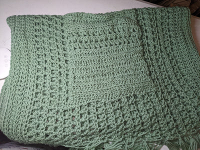 A picture of a soft green, handmade, crocheted shawl.