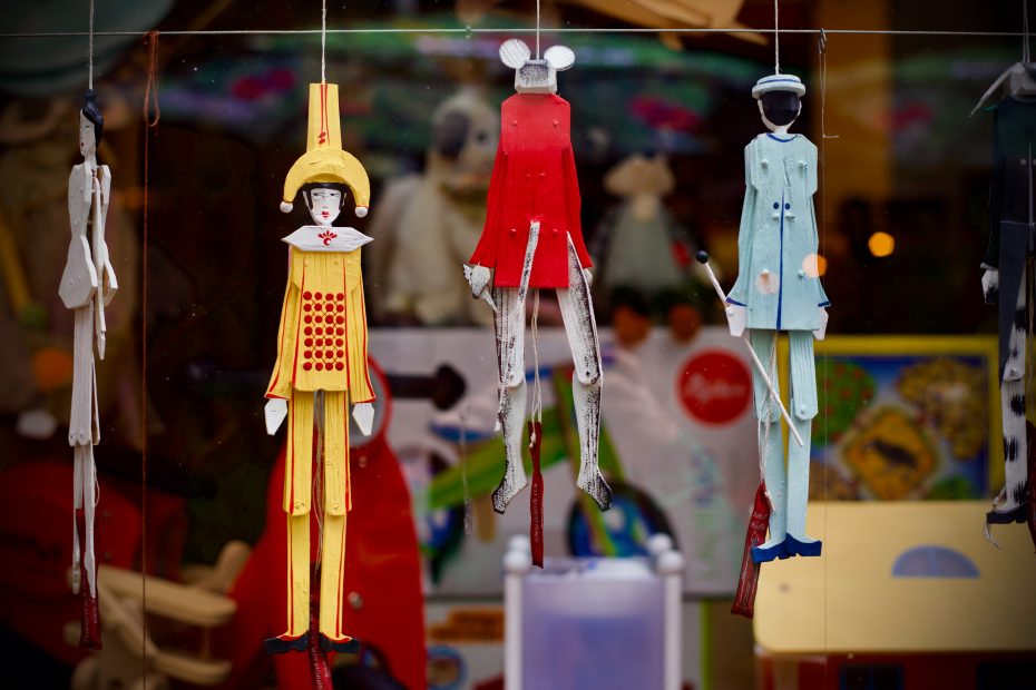 3 folk art marionette puppets in a store window. Photo by Aysegul Yasi on Unsplash.