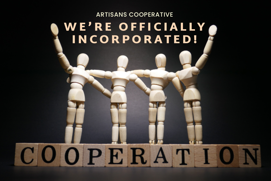 Image of four wooden artist's figures (like from IKEA) linking arms around each other, with the two outside ones raising their free arms in celebration. They are standing on alphabet blocks that spell COOPERATION. Above is the title We're Officially Incorporated! Artisans Cooperative