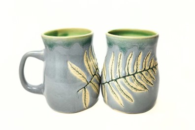 A photo of two blue-grey mugs with fern impressions on the sides. 