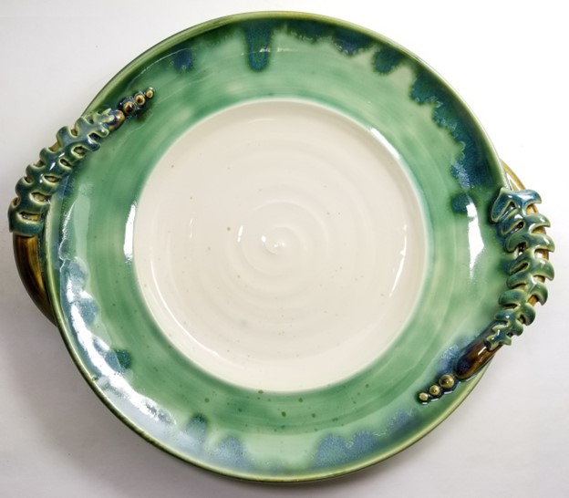 A photo of a white and green plate with molded ferns on two sides.