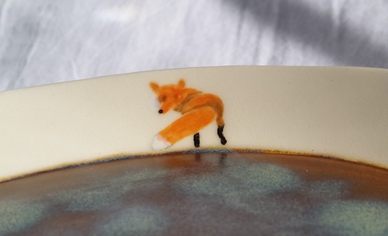 A photo of a painted fox on the inside of a dish.