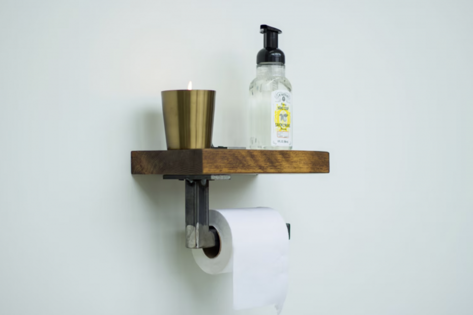 Photo of a toilet paper holder made from steel, with a dark thick wood shelf on top. A lit candle and soap dispenser sits on top of the shelf.