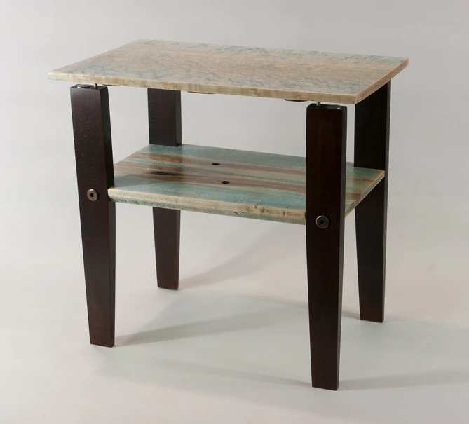 A photo of a small handmade table. It has four black legs, a gray, wooden top, and a smaller gray shelf. The top floats gently above the legs, utilizing opposing super magnets.