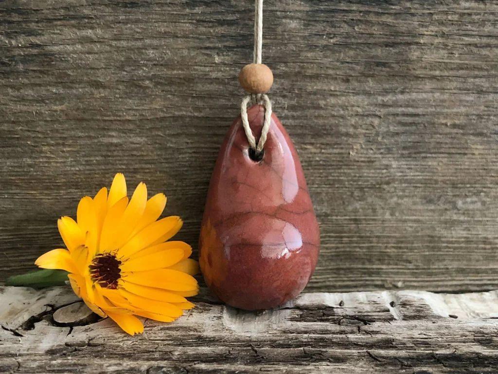 A rounded tear-drop shaped ceramic pendant with a dark red maroon glaze