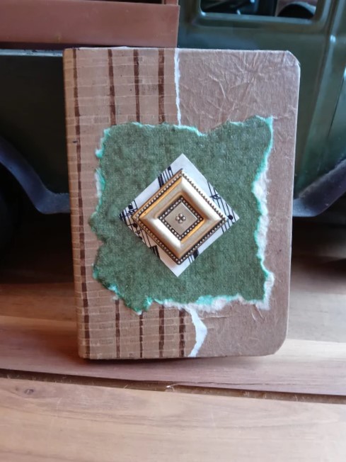 A mixed media notebook with live torn edge layers of verdigris copper paper and a miniature square diamond shape with 3D relief