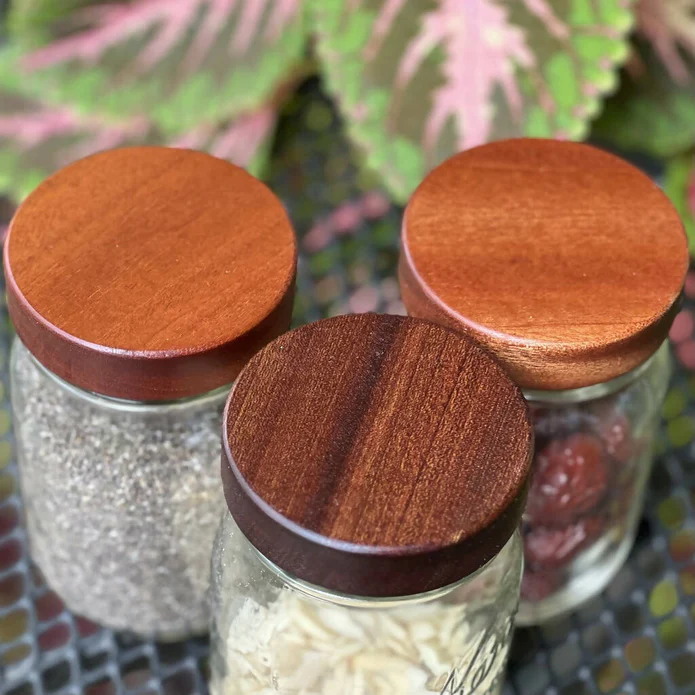 3 Mason jars filled with dry foods that have very beautiful hardwood lids.