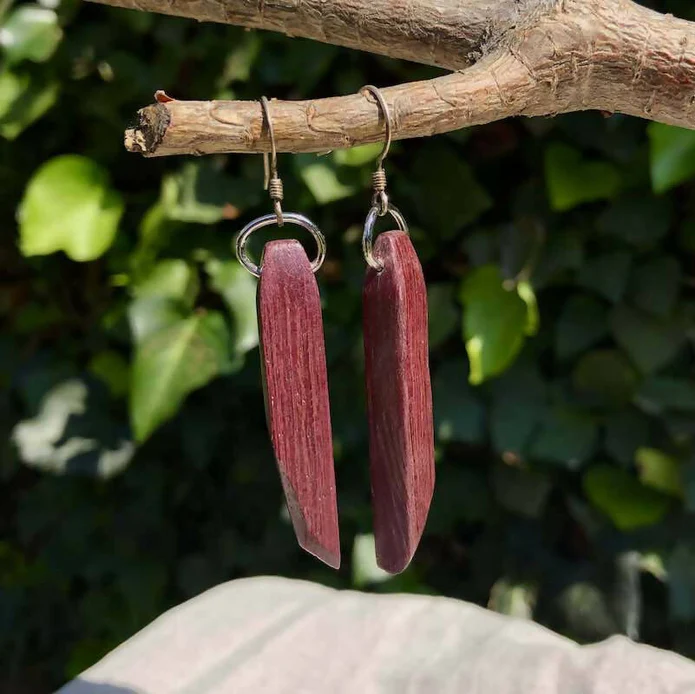 Handmade red wooden earrings cut in an elongated geometric shape.
