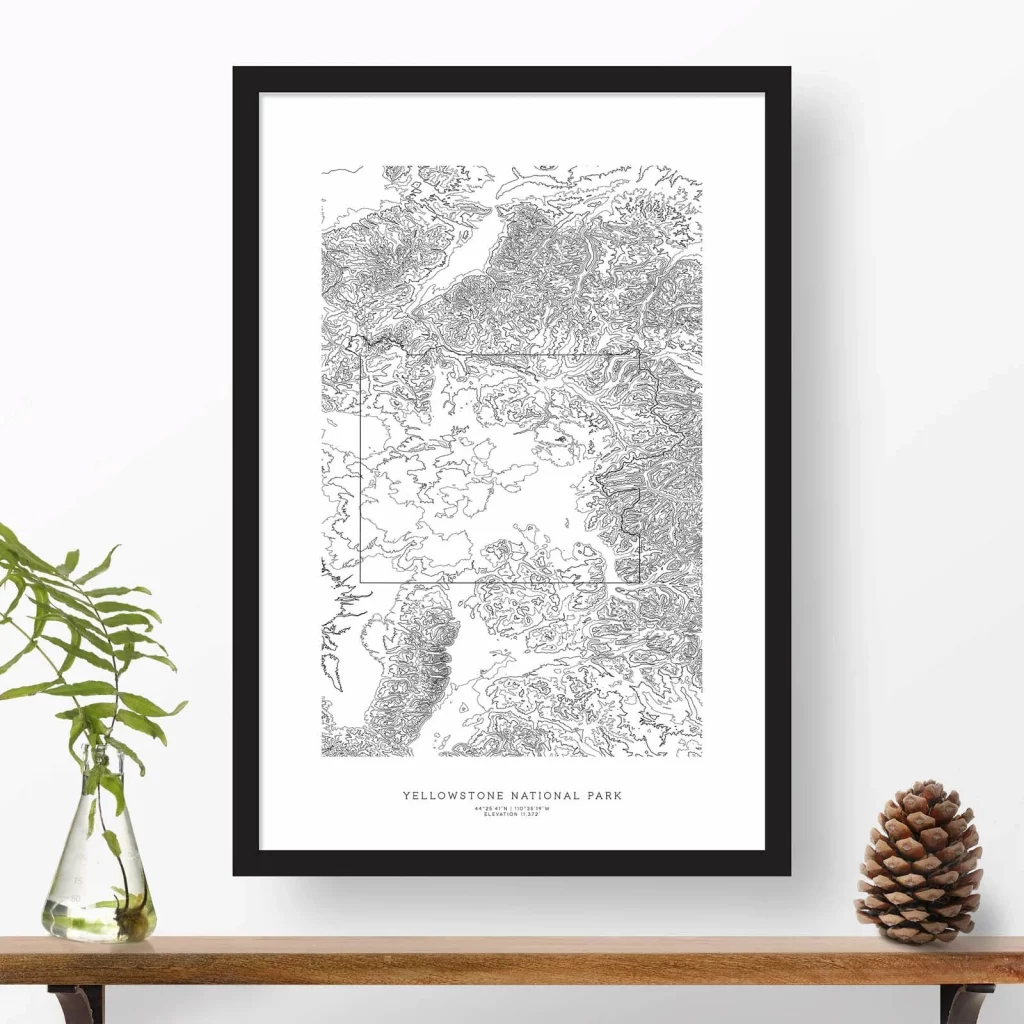On a wall in front of a wooden shelf, there is a black and white topographic map with text underneath that reads "Yellowstone National Park" in a black frame.