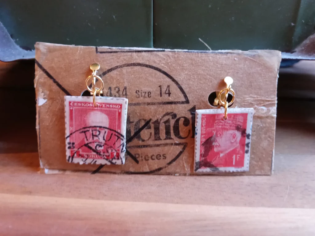 Clip on earrings made from canceled red British stamps that dangle down from a post