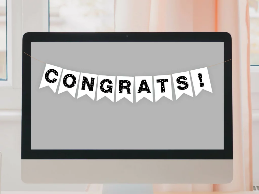 A slightly older iMac has a blank grey screen and there's a banner over it that says "CONGRATS!" with each letter/! being a bold font with dots on it. 