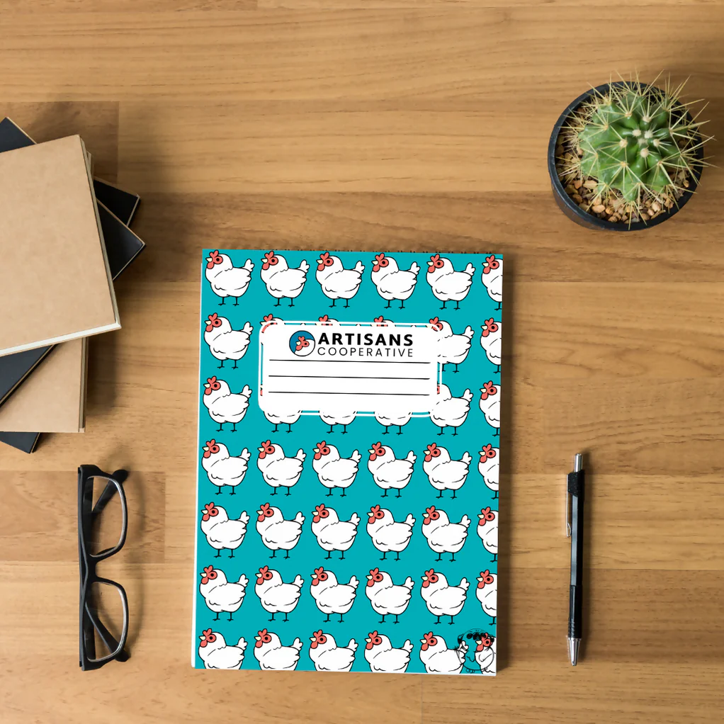 The cover of the notebook. This version is turquoise and is covered in the Artisans Cooperative chicken logo with the chicken looking over its right shoulder. In the center near the top is the space for writing something on the cover like typical composition notebooks - a white rectangle with three lines. Within that is the Artisans Cooperative logo with name.