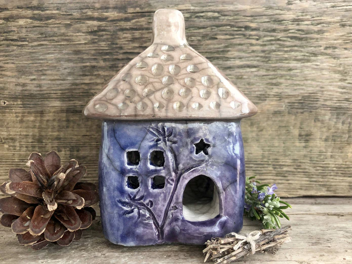 A small purple ceramic incense holder in the shape of a small house. The Raku firing gives it a crackled look.
