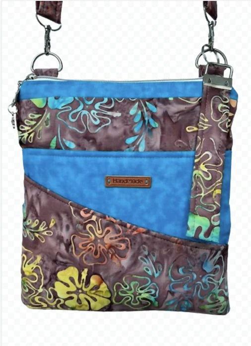 A small square bag made from chocolate brown fabric with tropical leaves printed in yellows, blues, and greens.