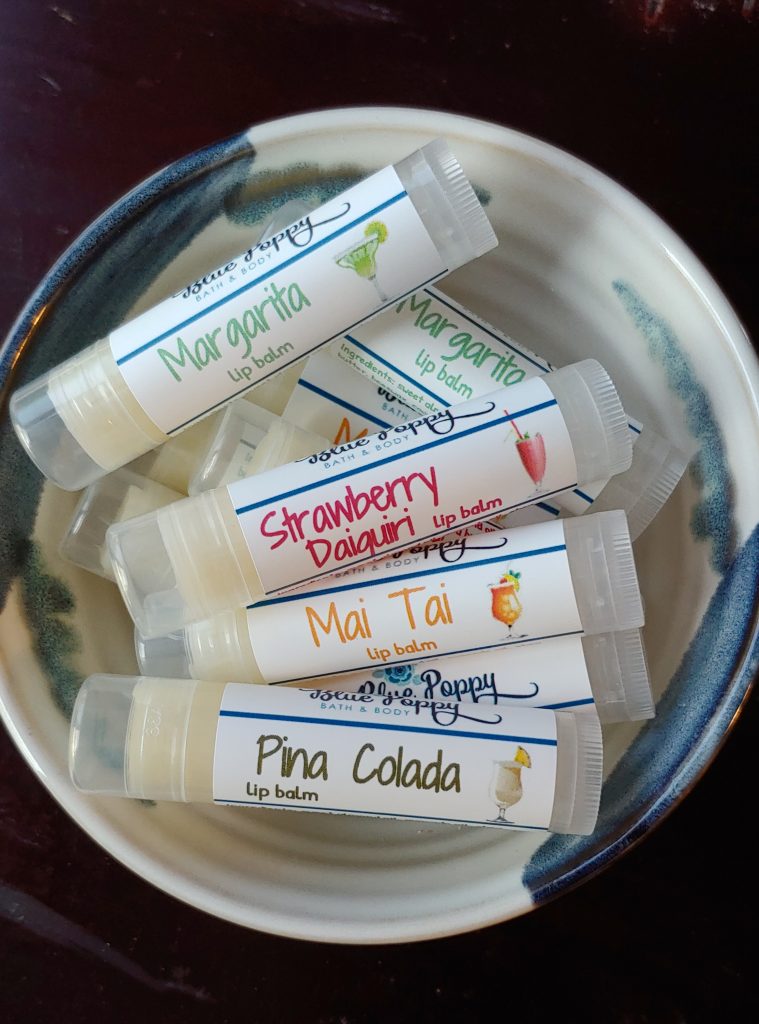 A bowl full of Blue Poppy Bath and Body Works lip balms or chapsticks in creative cocktail flavors like Mai Tai and Strawberry Daiquiri