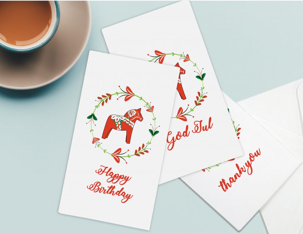 Picture of a Swedish theme inspired greeting card with a red horse in Swedish folk art and the words Happy Birthday and God Jul on the greeting cards in red script.