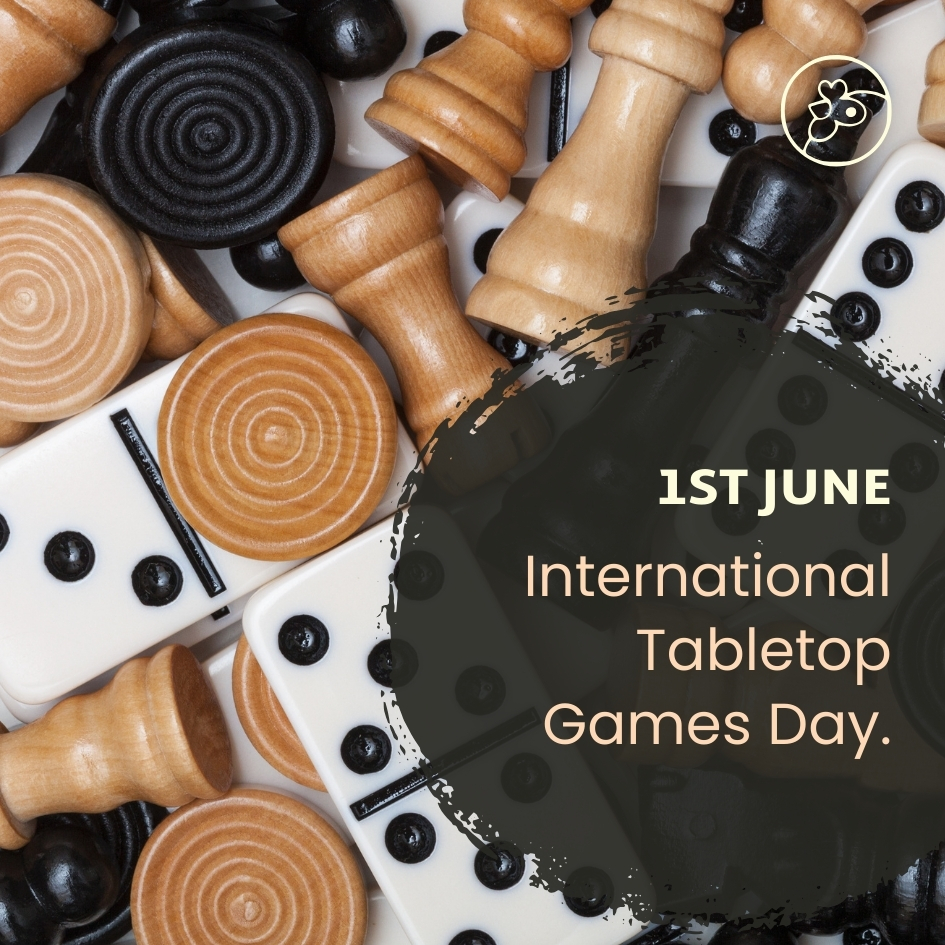 Chess pieces, dominoes and wooden counters mixed together in a jumble with a dark circle and white text that reads 1st June International Tabletops Games Day.