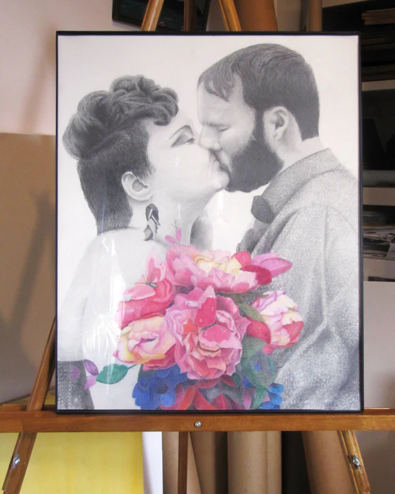 A framed wedding portrait in graphite pencil with a colored pencil drawn flower bouquet 